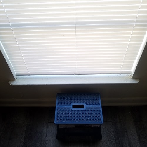 Large Vertical Window with a blue stool under the ledge.